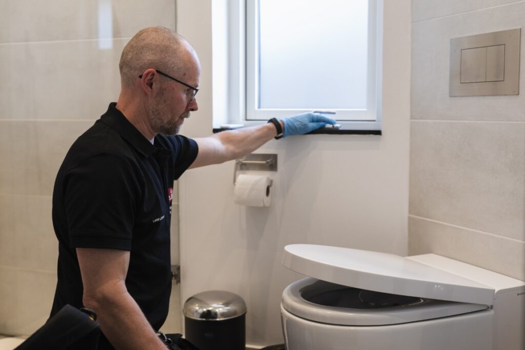 VVS-installatør arbejder på nyt badeværelse med montering af toilet og installation